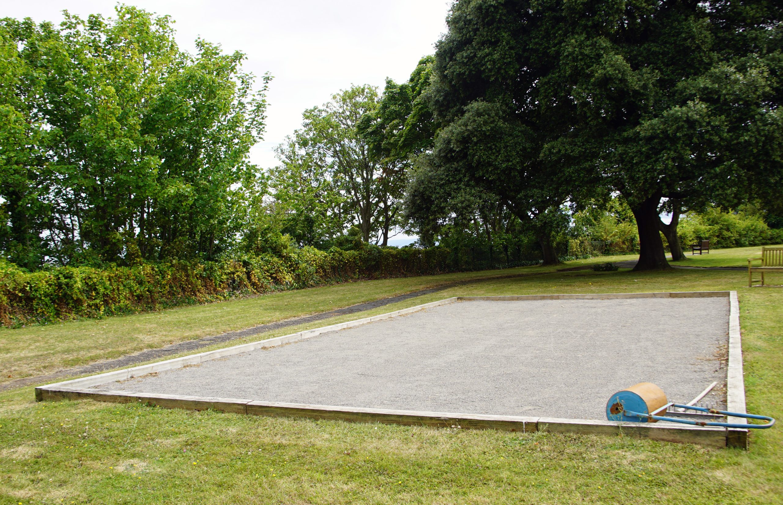 Hayes Point boules court with gravel surface and wooden borders, surrounded by trees and open greenery.